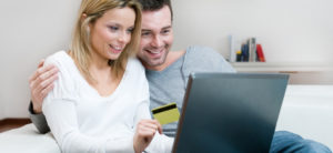 Couple looking on laptop shopping for a sewing machine for quilting , while woman's hand holding a credit card.