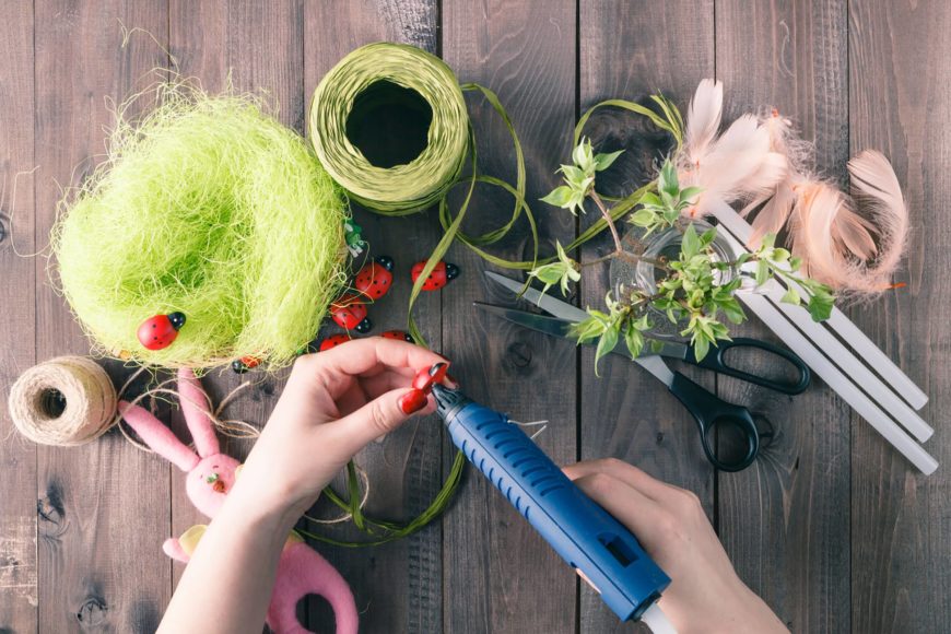 Crop image of woman's hand doing crafts with crafts materials on the wooden table