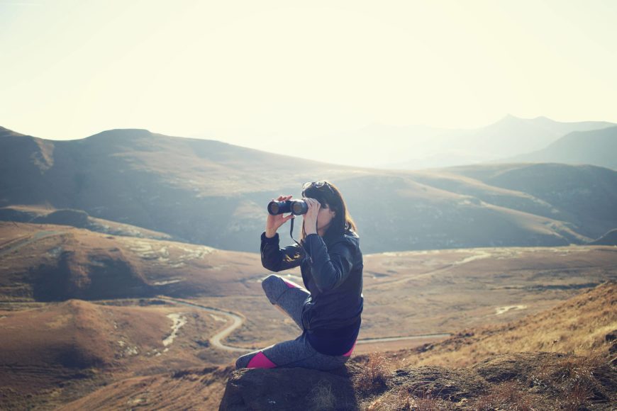 Woman using binoculars on the mountain