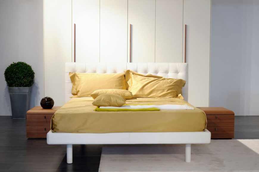 Bed with yellow cover and white headboard inside the room