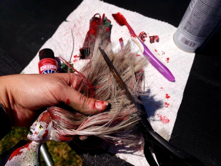 Barbie doll's messy hair cutted out using a scissor.