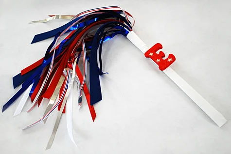 Sparkless sparklers for kids for the Fourth of July using chopsticks, ribbon and party garland