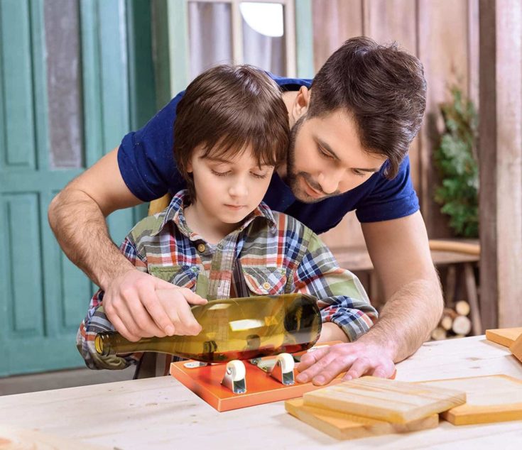 Man guiding his son on how to do bottle glass cutting.