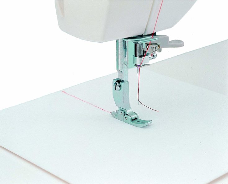 a closeup shot of a cloth, sewing needle, presser foot - stitching process of a sewing machine