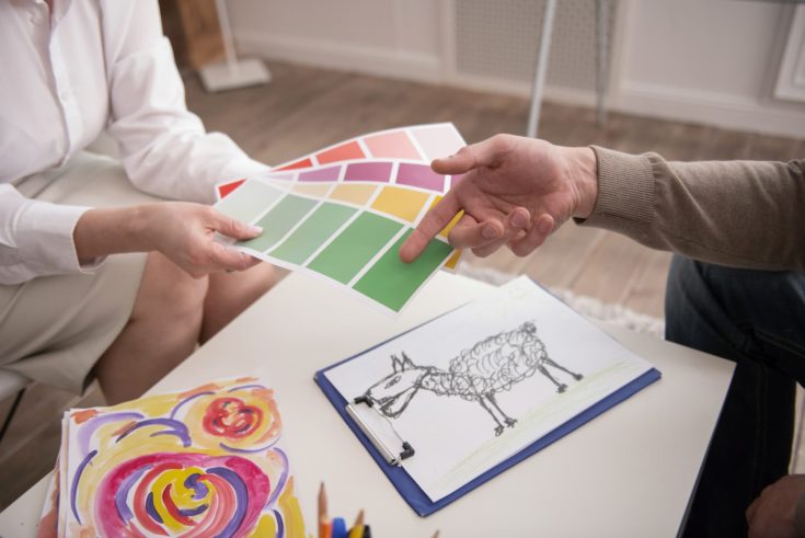 Color test. Close up of male young hand choosing color while female hands holding pallet