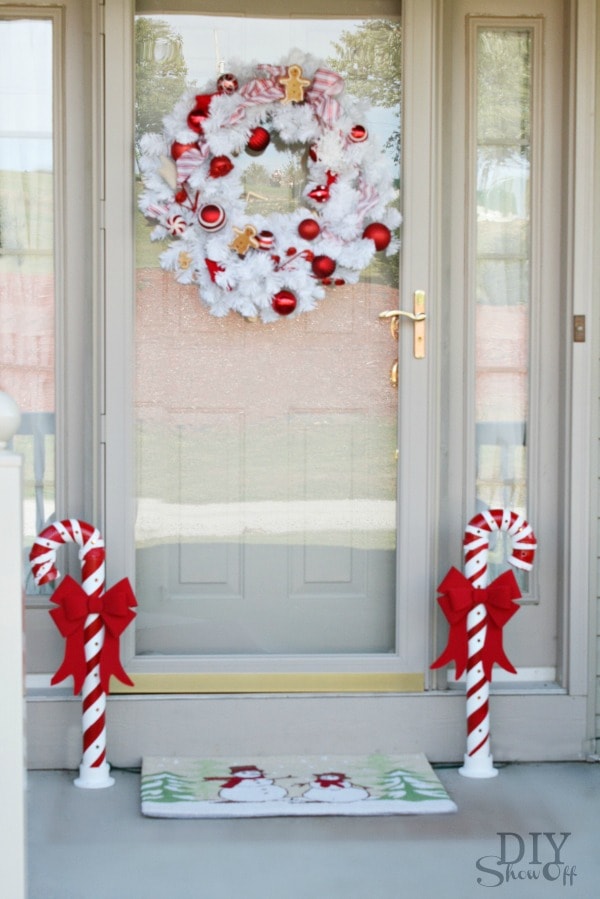 DIY Show Off PVC Candy Cane with red ribbon in front of a white door