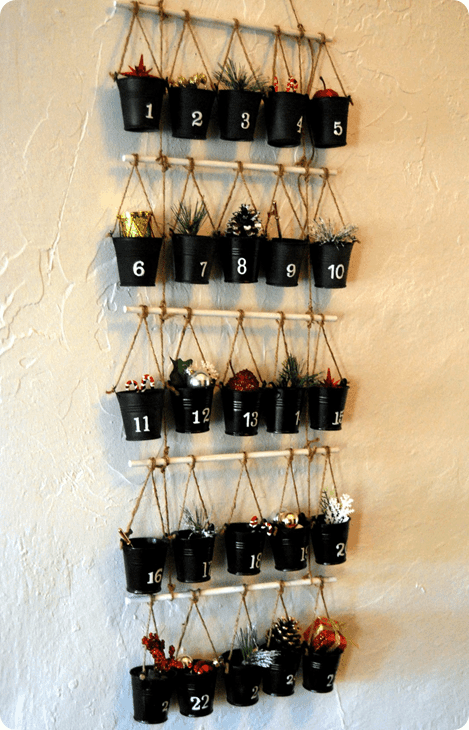 Small black pots tied in stick hang on a white wall