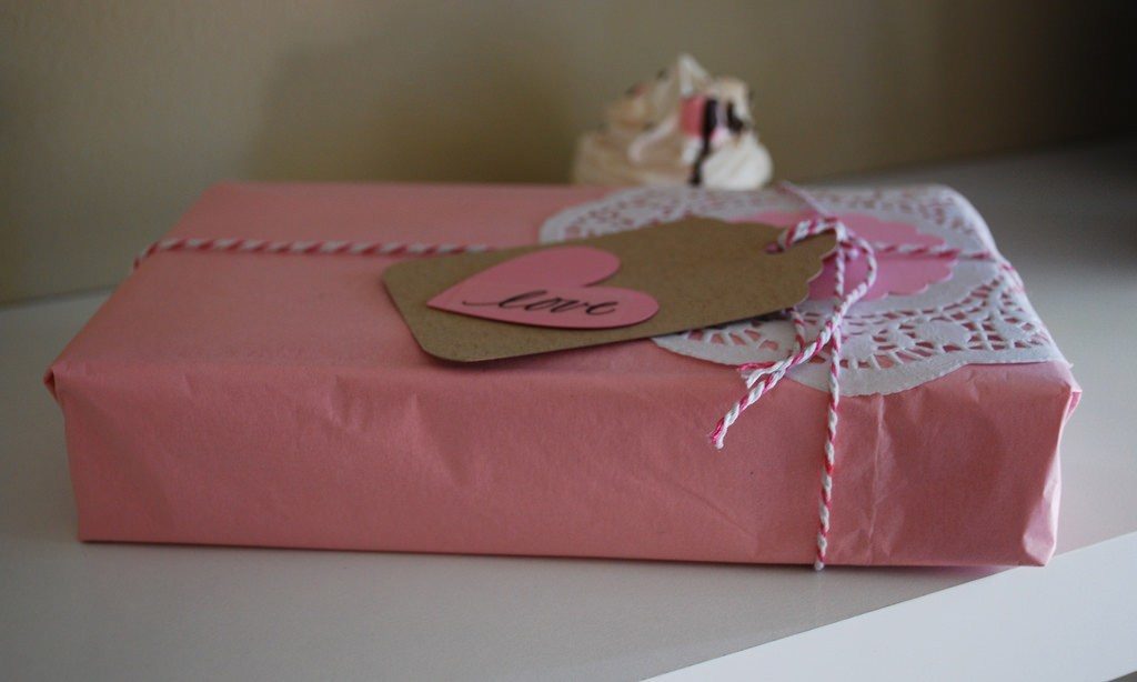 Pink wrapping paper with white and pink string and brown tag with pink heart with love note