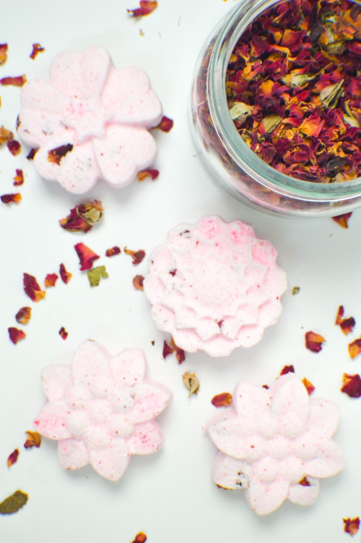 DIY floral bath bombs with a jar of dried leaves on the side.