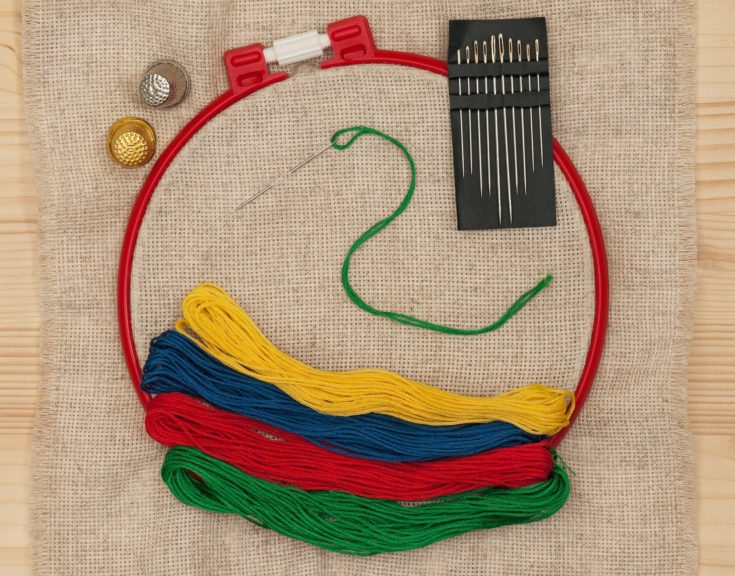 Bright embroidery accessories with sewing needles over outline background