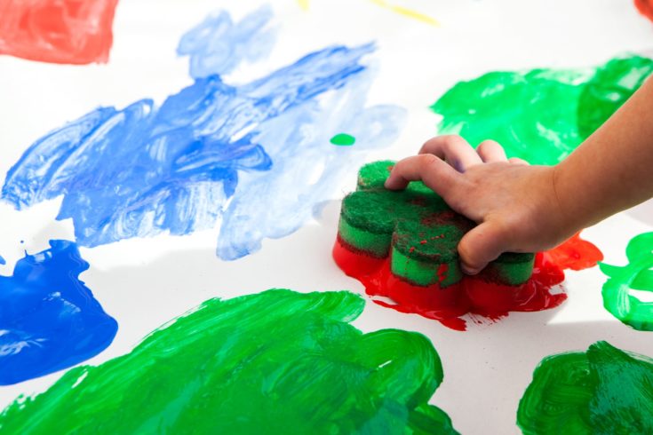 Child hand painting red colour on paper