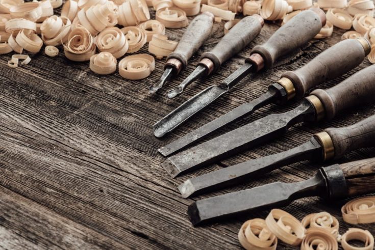 Old carving and woodworking tools and wood shavings on a vintage workbench: carpentry, woodworking and craftsmanship concept