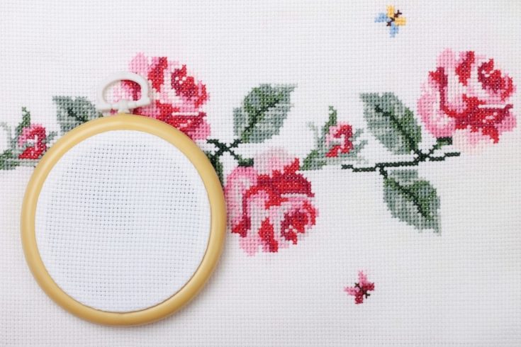 background with embroidered cross on canvas patterns of flowers roses