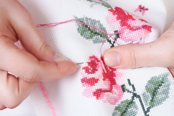 Women's hands with a cross embroidered on the fabric patterns of flowers roses