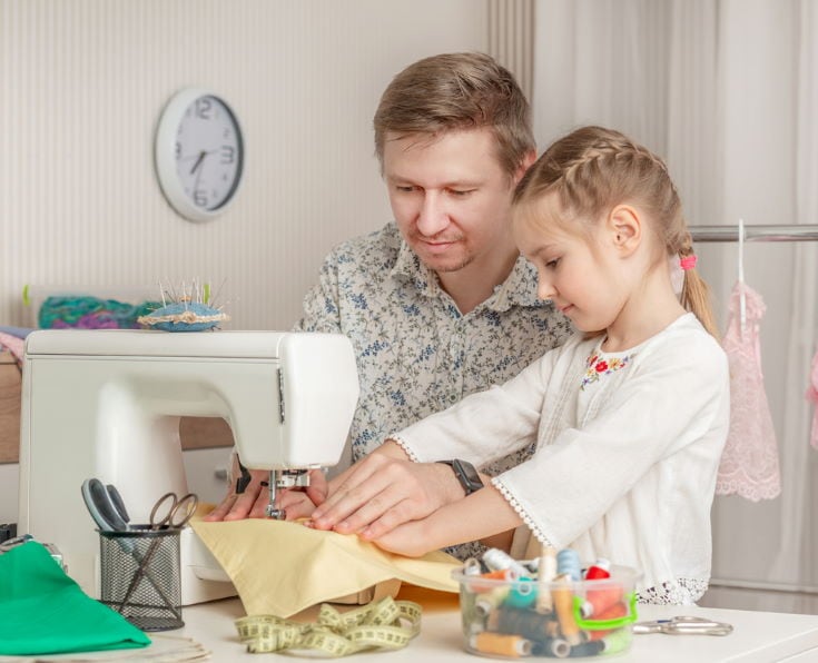 cute little girl and her dad in a sewing workshop