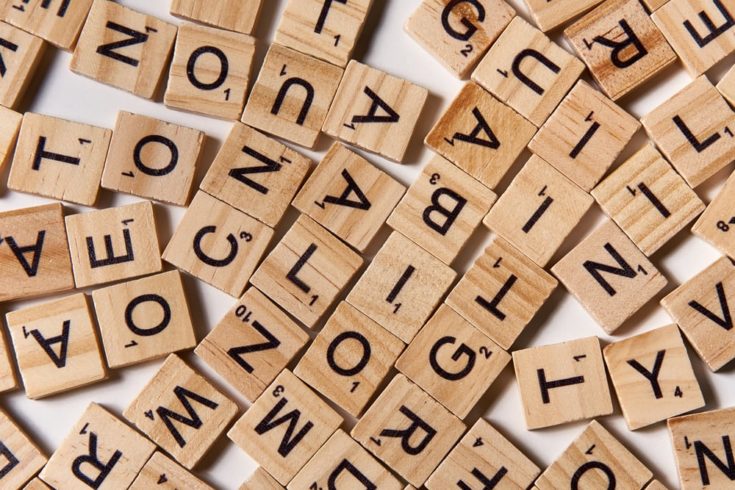 Background of wooden alphabet letters scattered randomly on white background