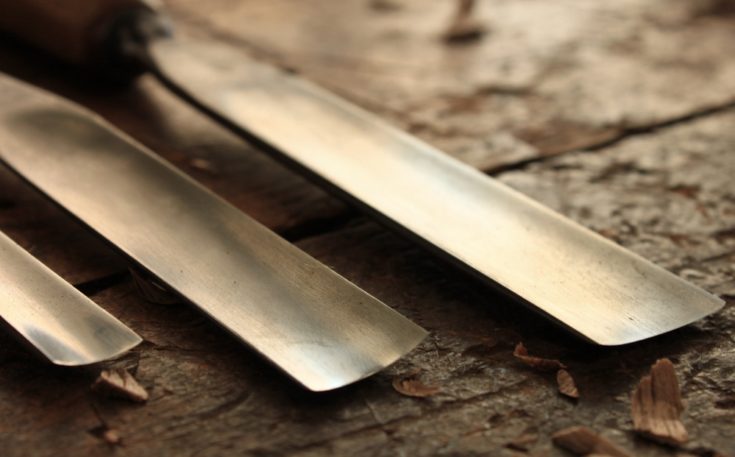 Carpenter wood chisel tool with loose shavings on old weathered wood.