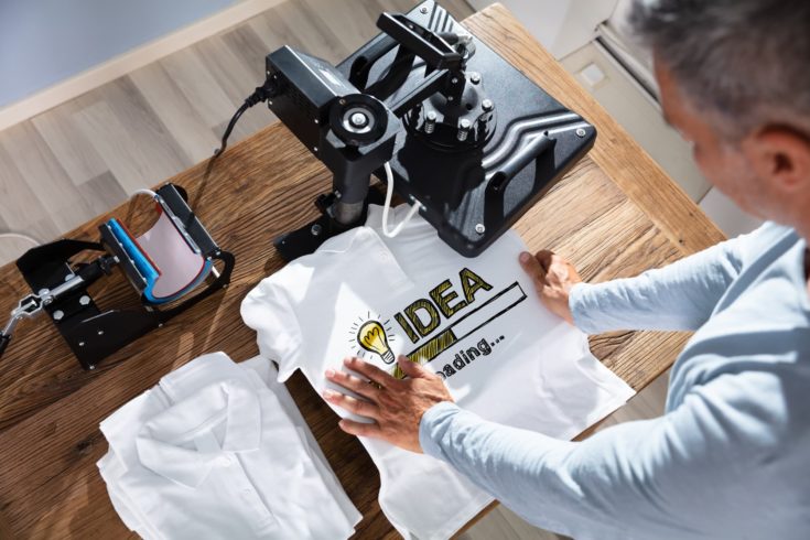 Man Printing Image On T-Shirt In Workshop