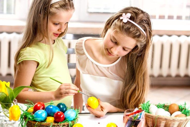 Happy children paint Easter eggs at home.