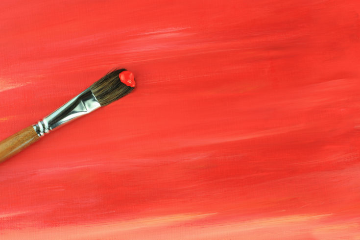 Paintbrush against a red abstract painting.