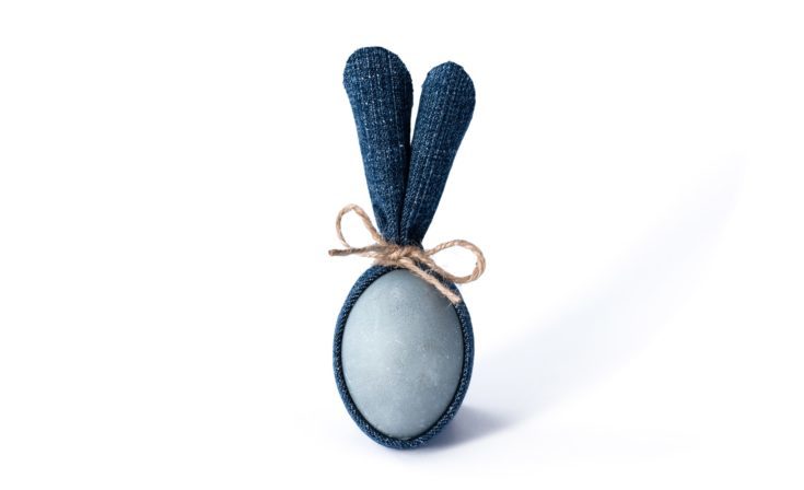 Easter egg with blue denim bunny ears on white background. DIY idea. Minimal happy Easter concept.