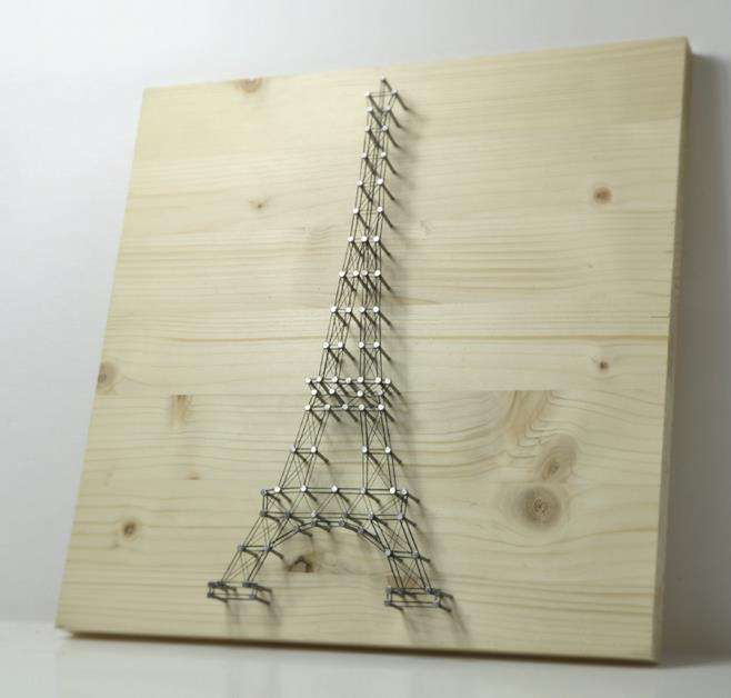 Eiffel Tower string art on wooden plank.