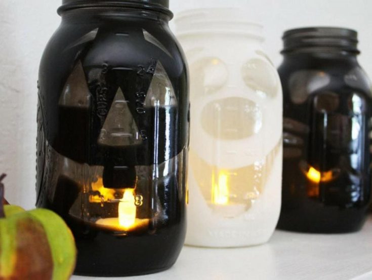 DIY Halloween luminaries sprayed black paints on the whole jar and putting stickers for the desired output of designs.