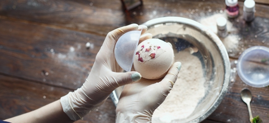 creating a diy bath bomb. Hands with white gloves holding a bath bomb coming out of its mold