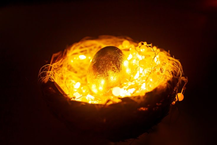 Golden egg in the nest with lights over dark background, mystery easter concept