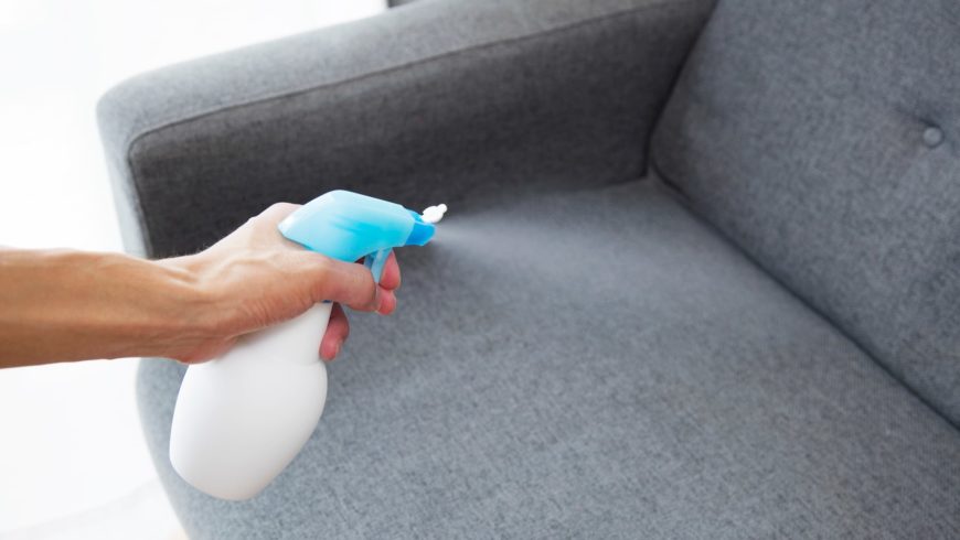 Woman's hand spraying on the couch