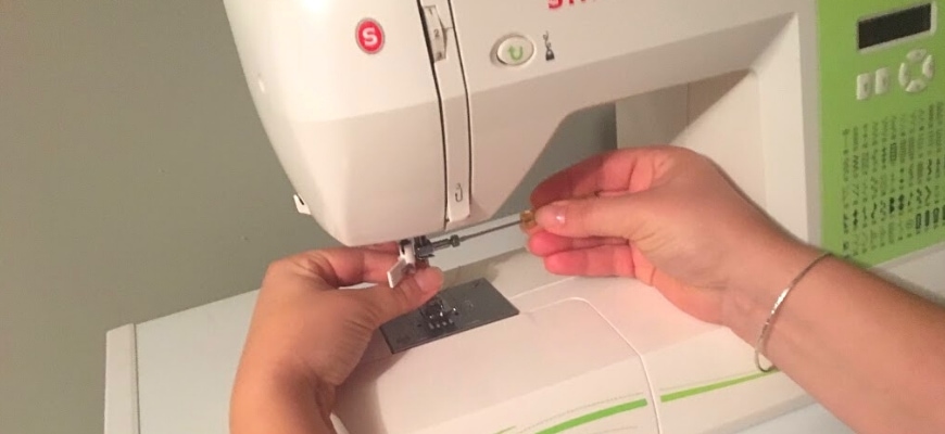 A person's hand holding a small screwdriver to tighten the needle