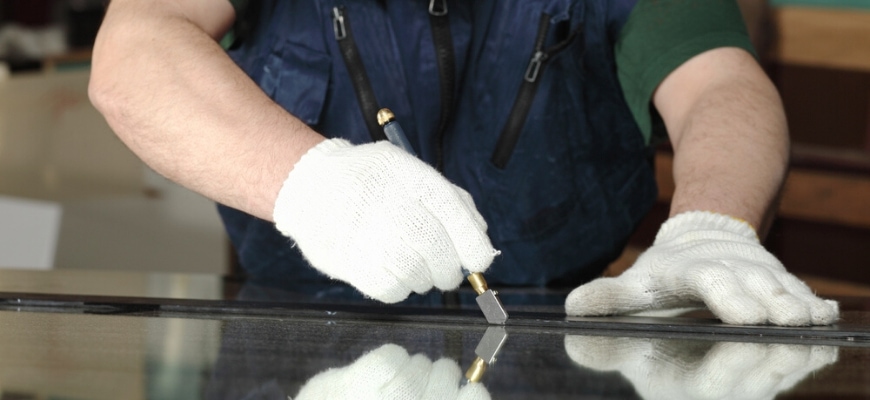 Cropped shot of man's hand holding a glass cutter on a glass.
