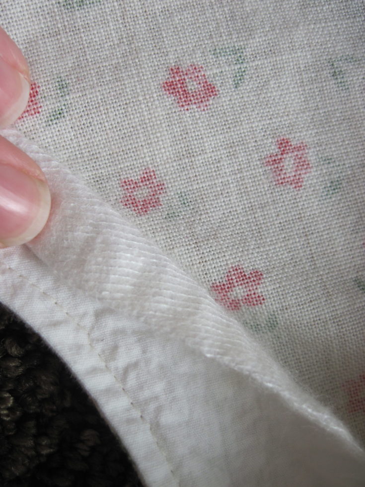 Close up shot of woman's hand sewing interfacing at hem.