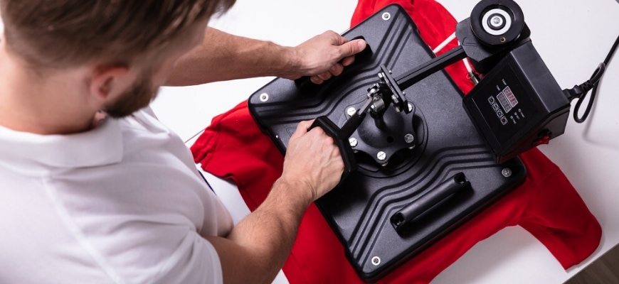 Top view of man pressing a heat press to red t-shirt.