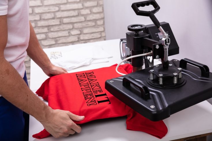 Man printing on a red t shirt in workshop