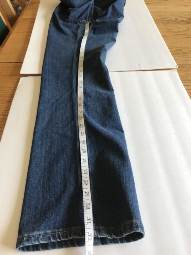measuring the jeans on the table using tape measure