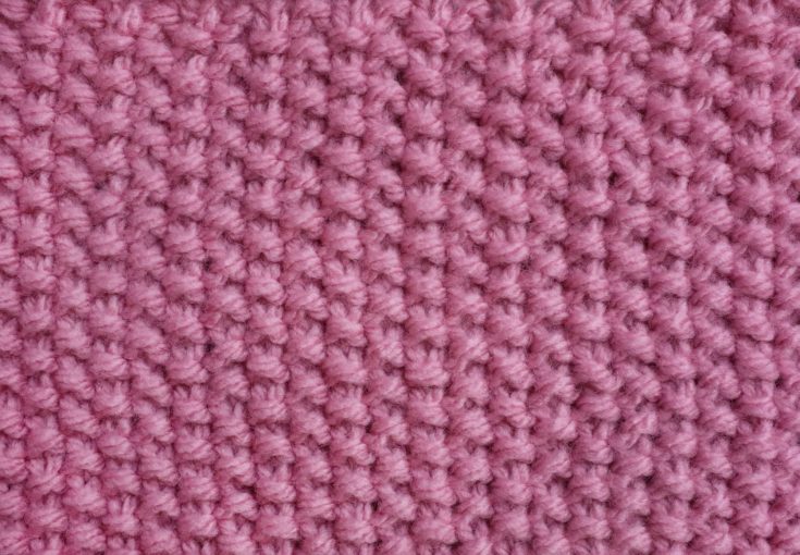 Moss stitch knitting in pink yarn as an abstract background texture