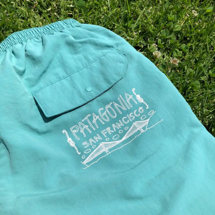 a cyan colored pants on a grass with patagonia san francisco print on it