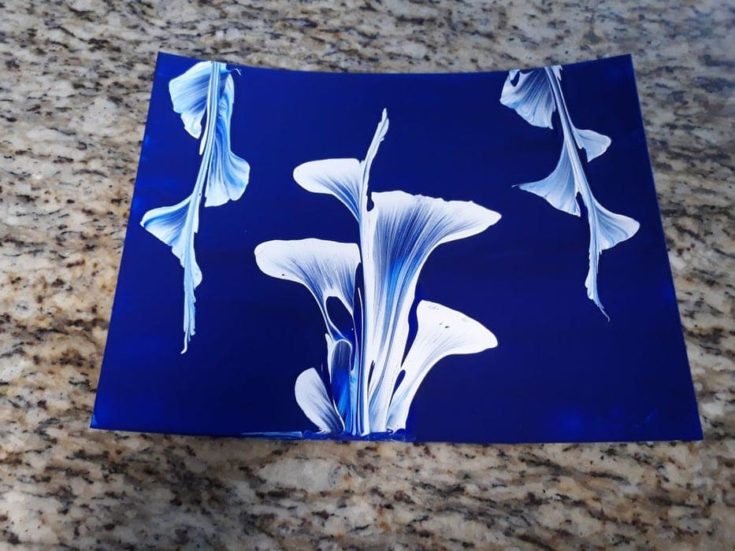 White flower on a blue canvass using a pull-string art.