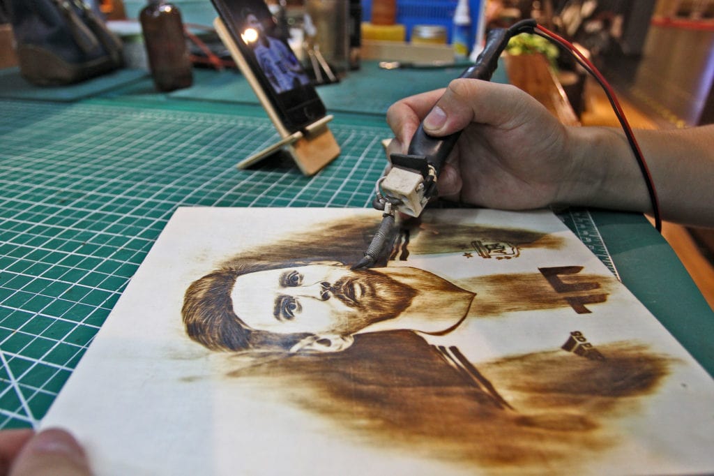 27-year-old Chinese man Peng Fang works with an art work of pyrography at his shop in Xi'an city, northwest China's Shaanxi province, 23 July 2018.