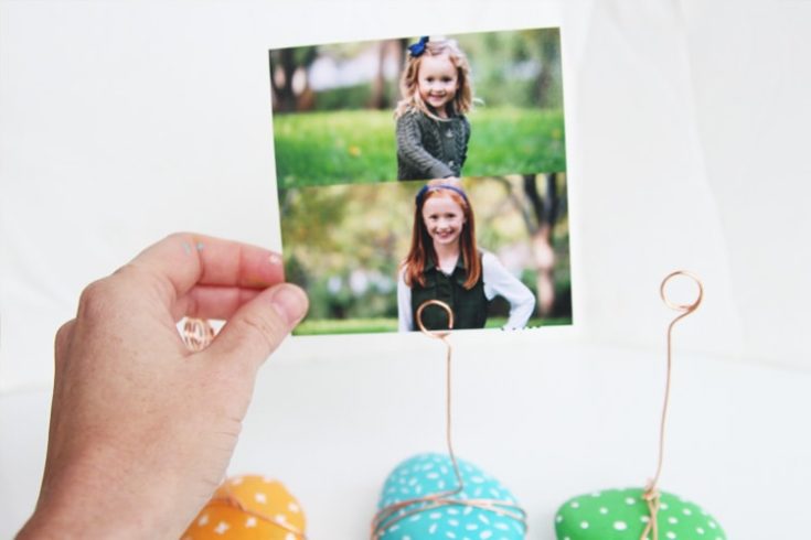 a person's hand holding a photo clipped in rock holders