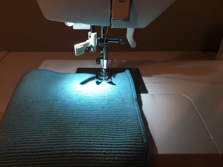 a blue fabric placed into the sewing machine ready for sewing