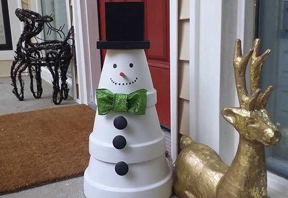 Terracotta Snowman with green bow tie besides a gold reindeer