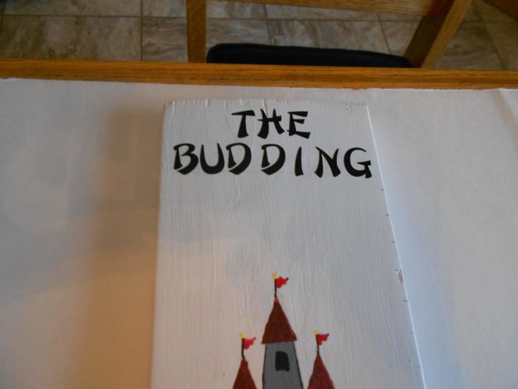 The Budding lettering on the a white painted board with a castle drawing below