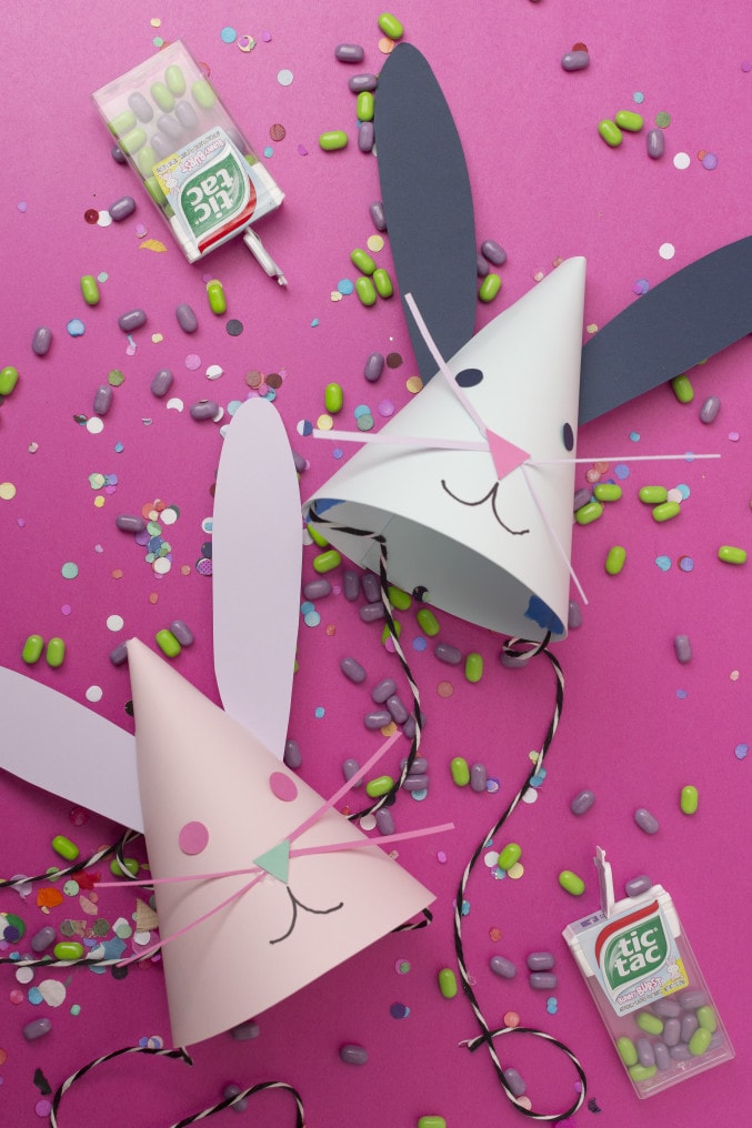 DIY Bunny design party hats with tictac candies spread on a pink background.