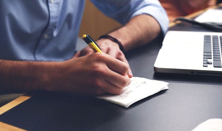 man writing on paper