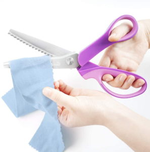 woman's hand cutting the cloth using P.LOTOR Sewing Pinking Shears