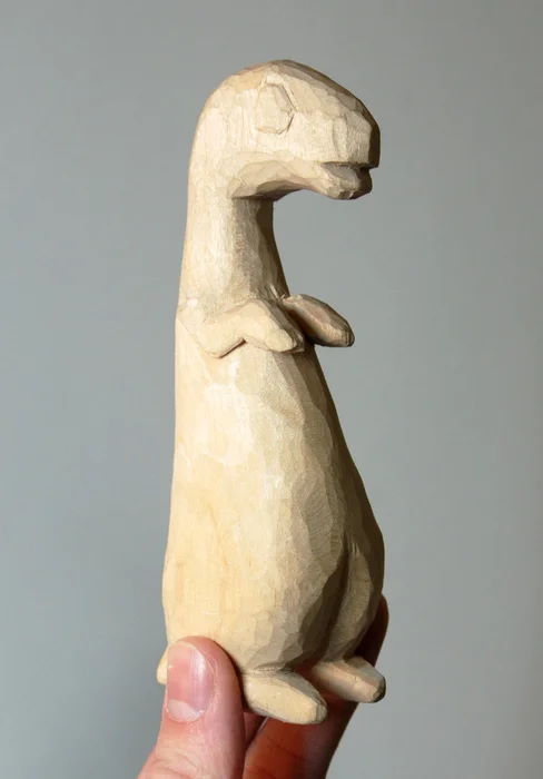 woman's hand holding dinosaur wood toy
