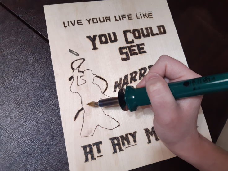 woman's hand making design on the wood