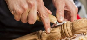 man's hand carving the wood